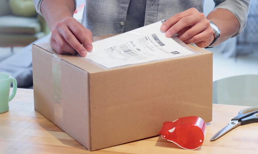 A man places a shipping label on a cardboard box.