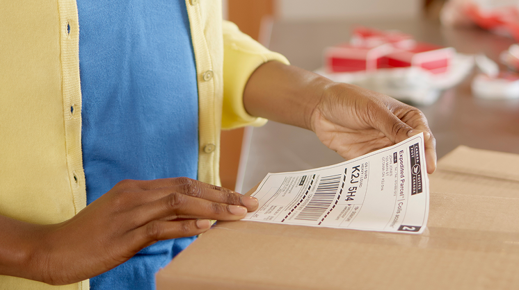 Person placing a shipping label on a parcel box