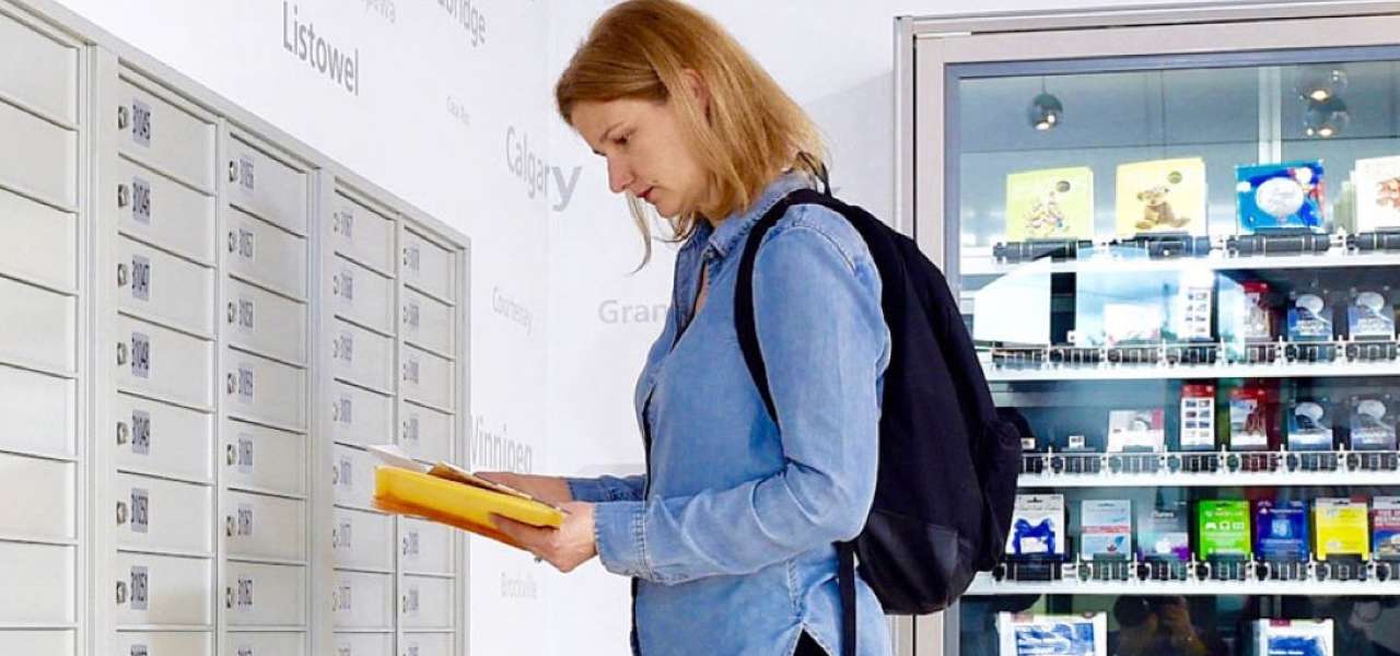 Une femme dans un bureau de poste examine une petite pile de courrier récupérée dans sa case postale de Postes Canada